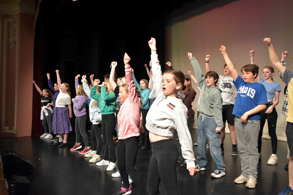 Cast punching the air during an energetic number